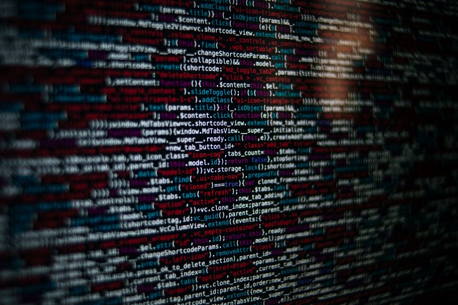 Close-up of source code on a screen, in red, white and blue text on a dark background
