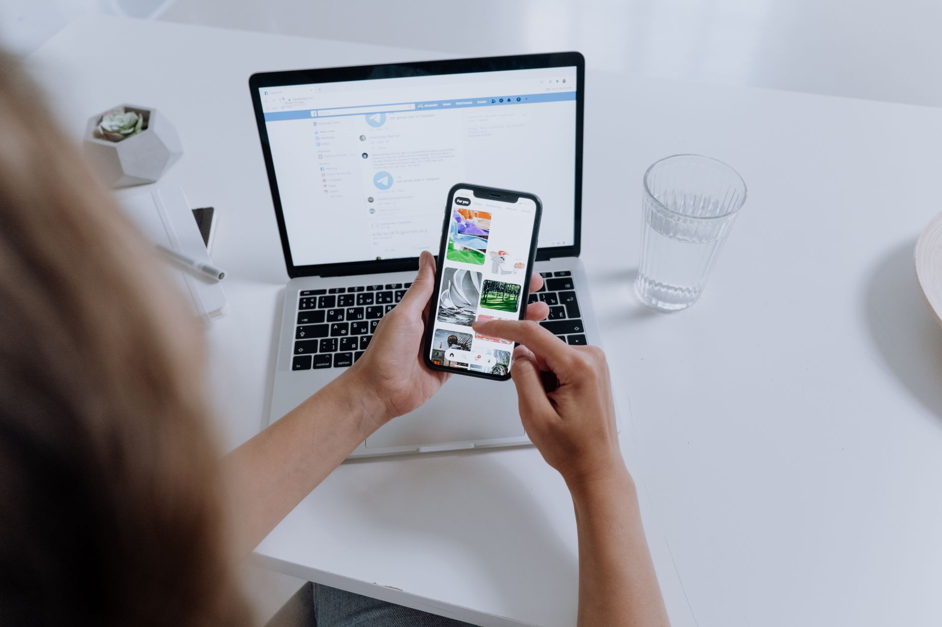 A person using an app on a phone in front of a laptop