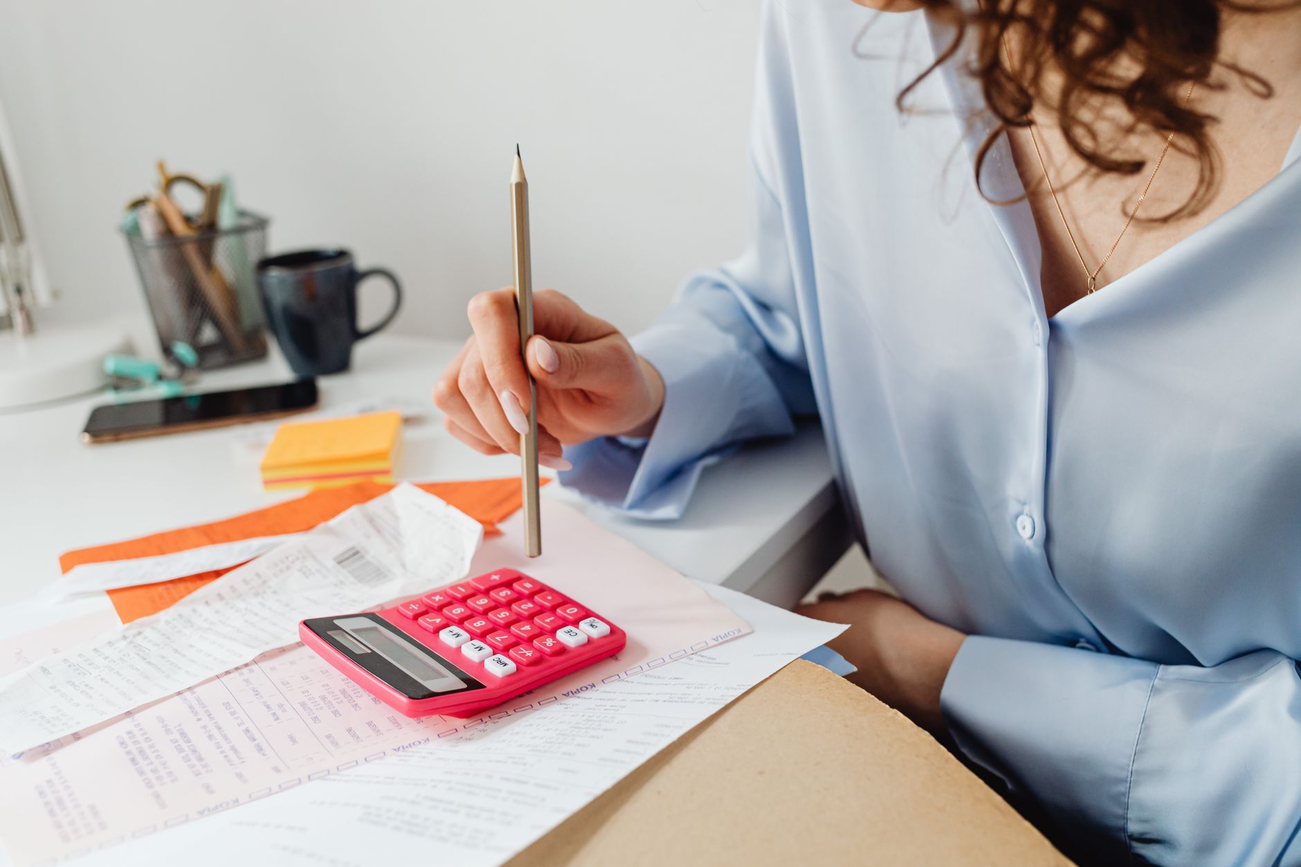 A business owner working through invoices with a calculator
